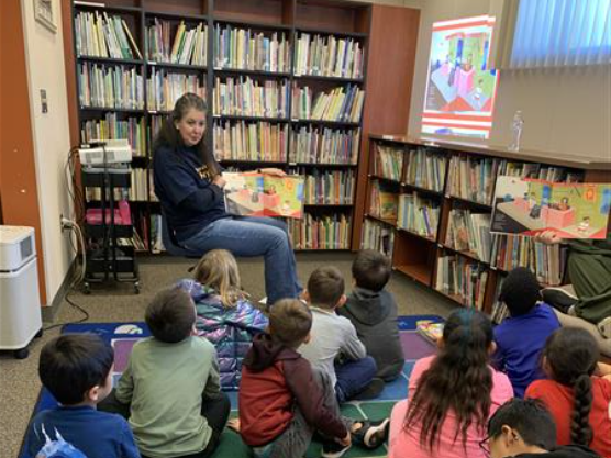 Rotary club member read a book to 1st graders in the library